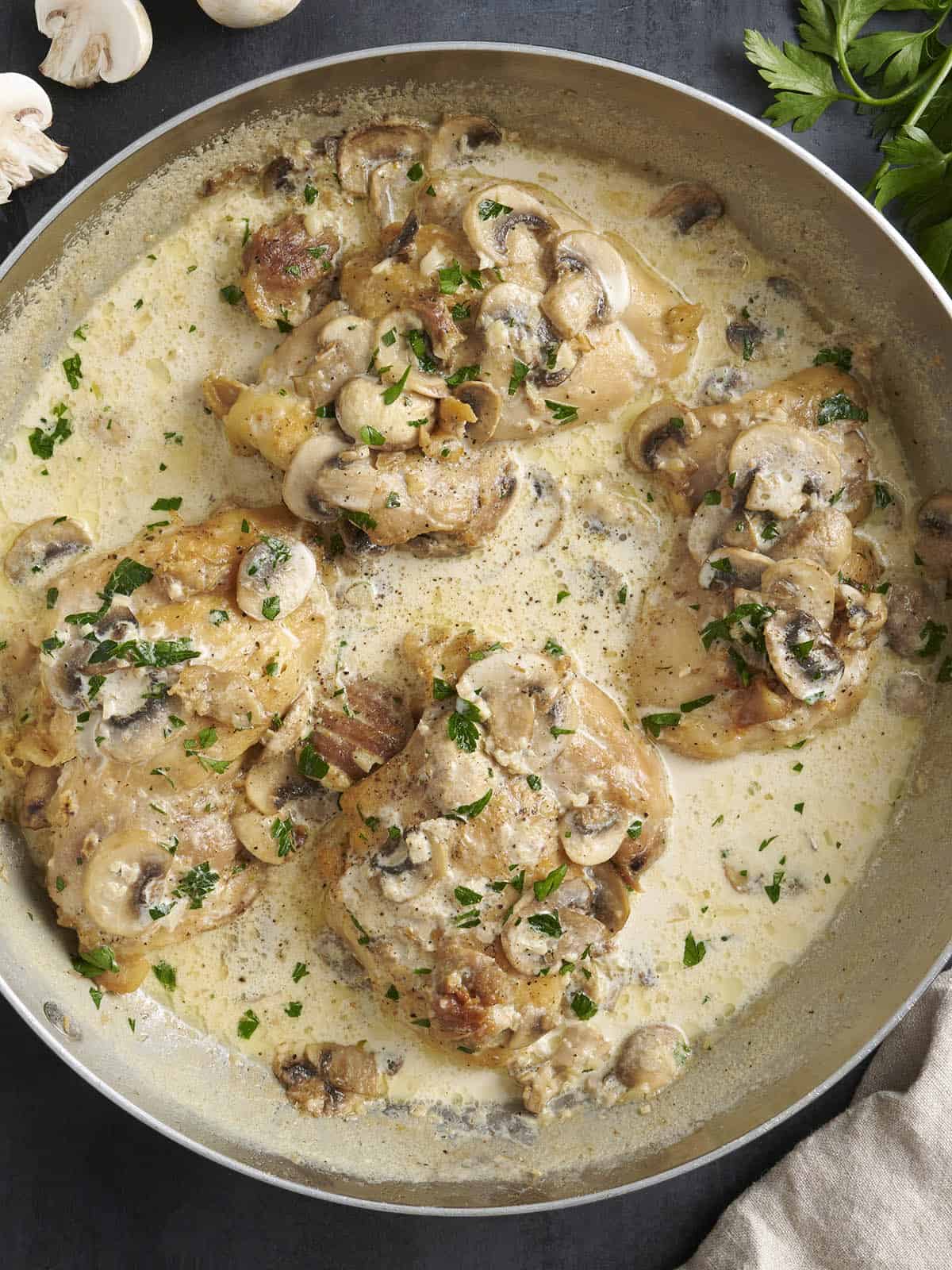 Vista aérea de pollo cremoso con champiñones en una sartén.