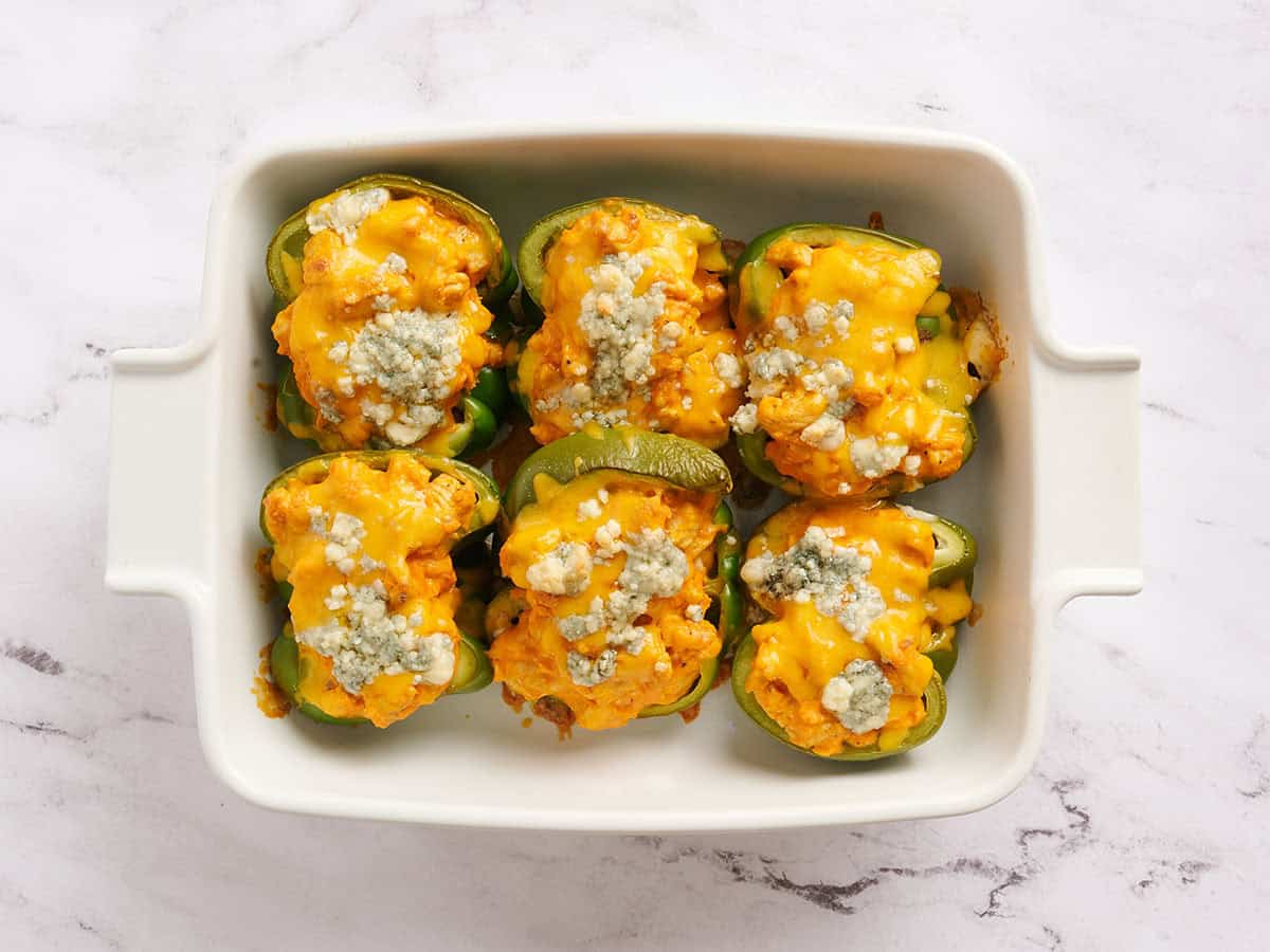 Pimientos rellenos de pollo Buffalo cubiertos con cebollas verdes.