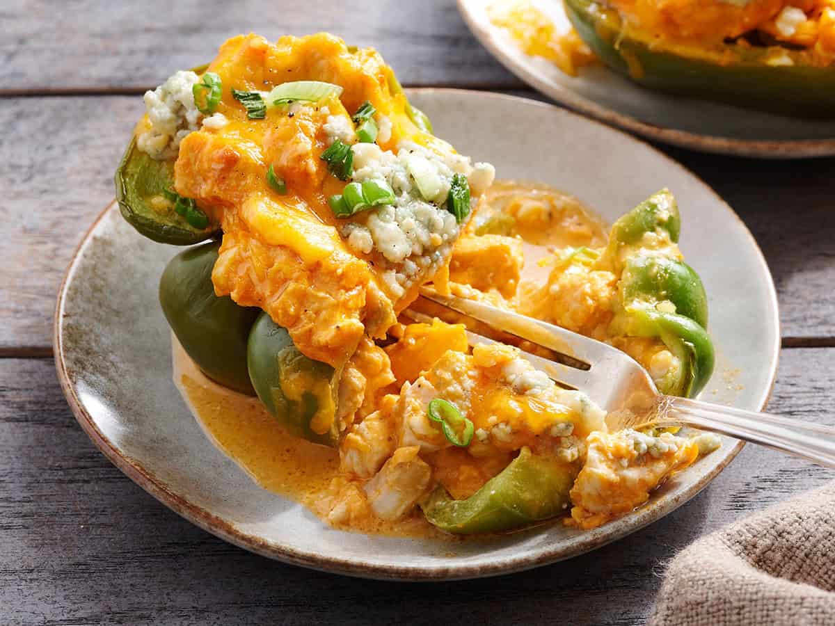 Side view of a buffalo chicken stuffed pepper sliced in half on a plate.
