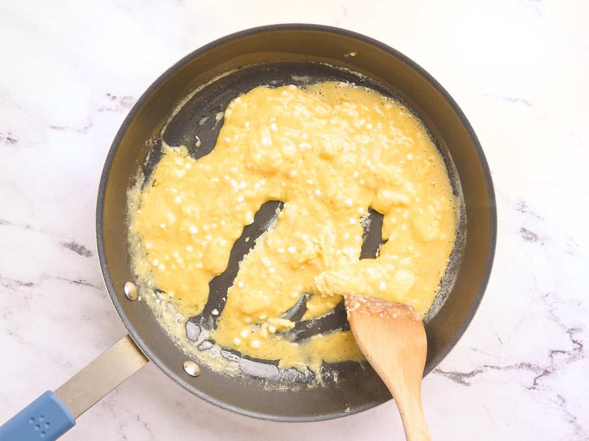 Huevos con requesón que se cocinan en una sartén.