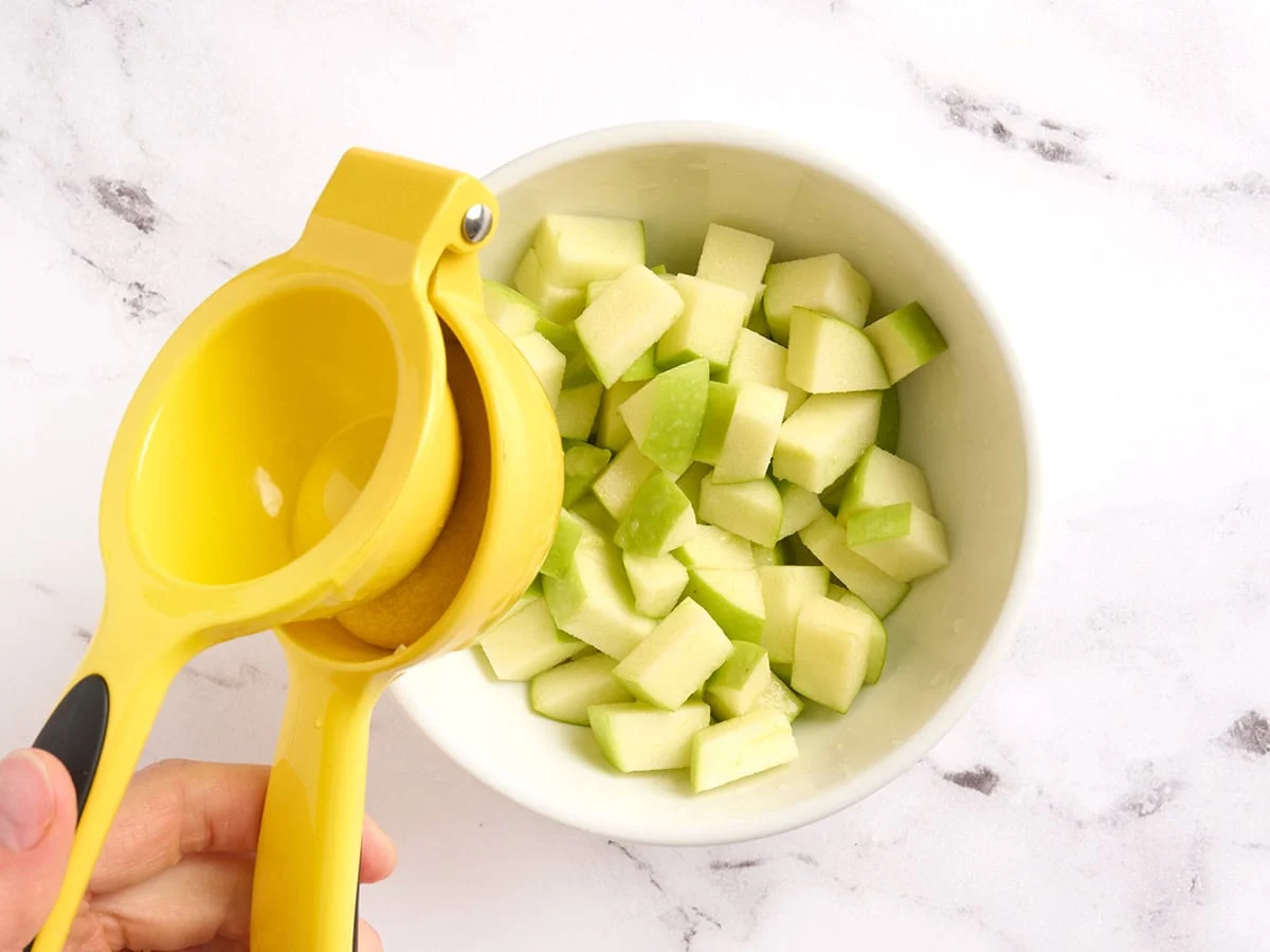 Exprimir jugo de limón en manzanas.