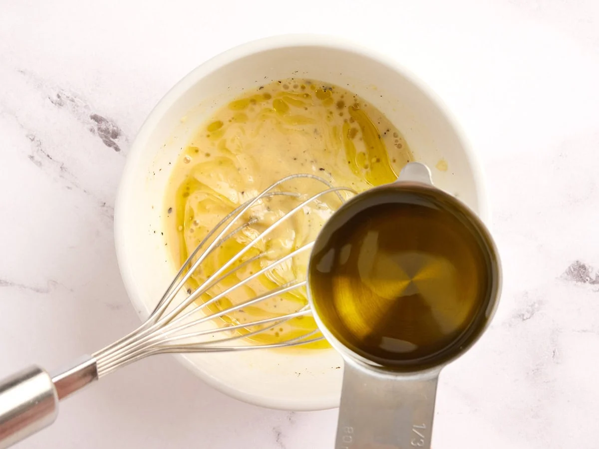 Se bate el aceite con un aderezo para ensalada de col rizada.