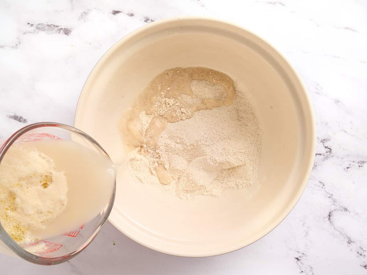 Se vierte una mezcla de levadura en un recipiente con ingredientes secos para hacer pan de pita.