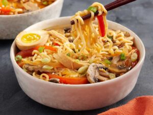 Side view of a bowl of slow cooked chicken and vegetables ramen.