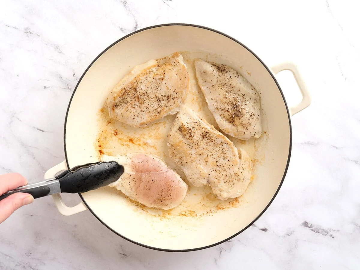 Filetes de pollo dorados en una sartén.
