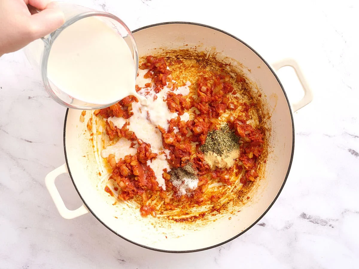 Se vierte la leche en una sartén para hacer una salsa de tomate cremosa.