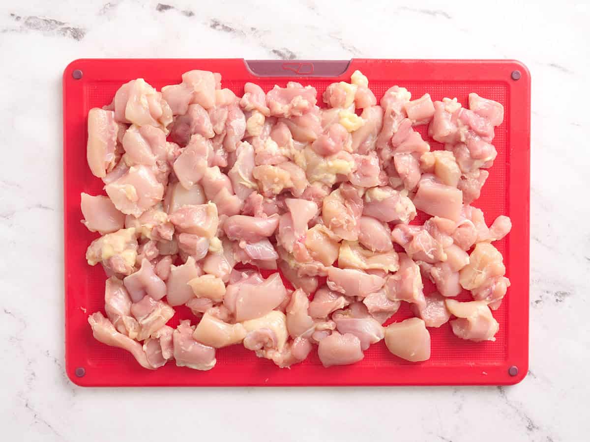 Pechuga de pollo cortada en cubitos sobre una tabla para cortar.