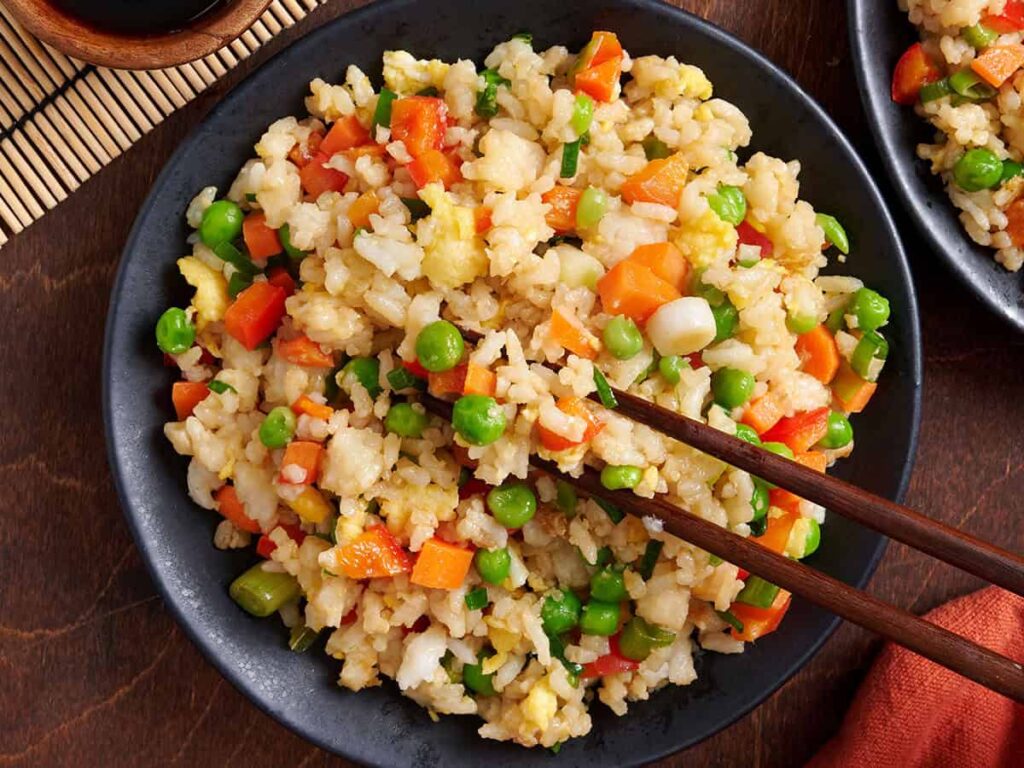 Overhead view of vegetable fried rice in a bowl with chopsticks.