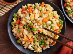 Overhead view of vegetable fried rice in a bowl with chopsticks.