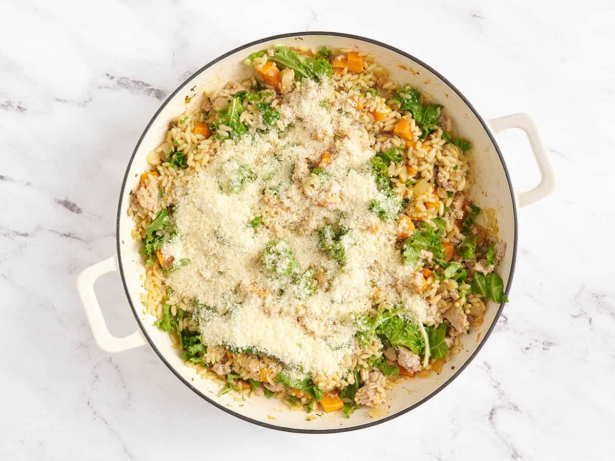 Parmesano añadido a una sartén de camote y pavo molido.