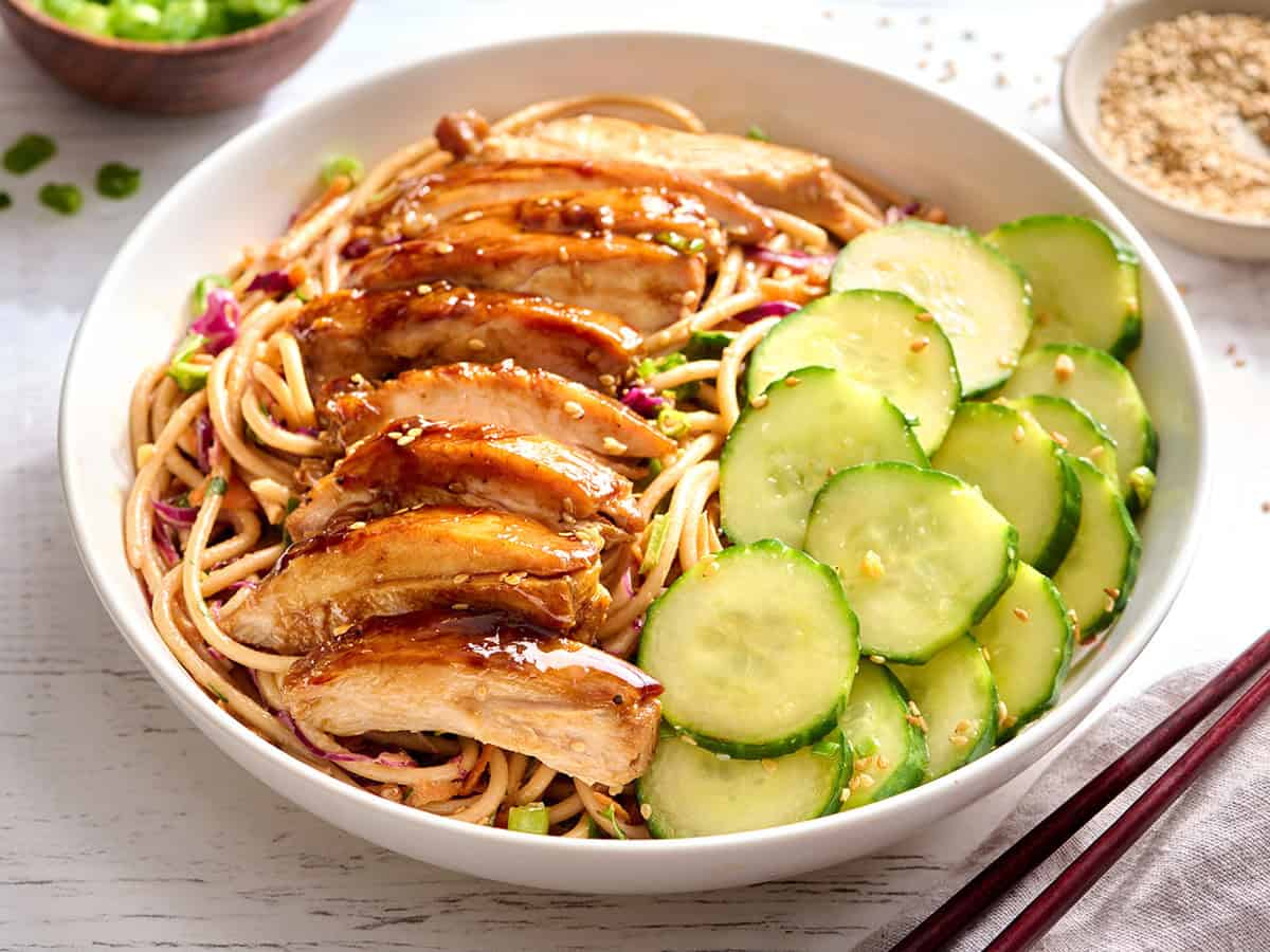 Pollo teriyaki sobre ensalada fría de fideos con ensalada tailandesa de pepino.