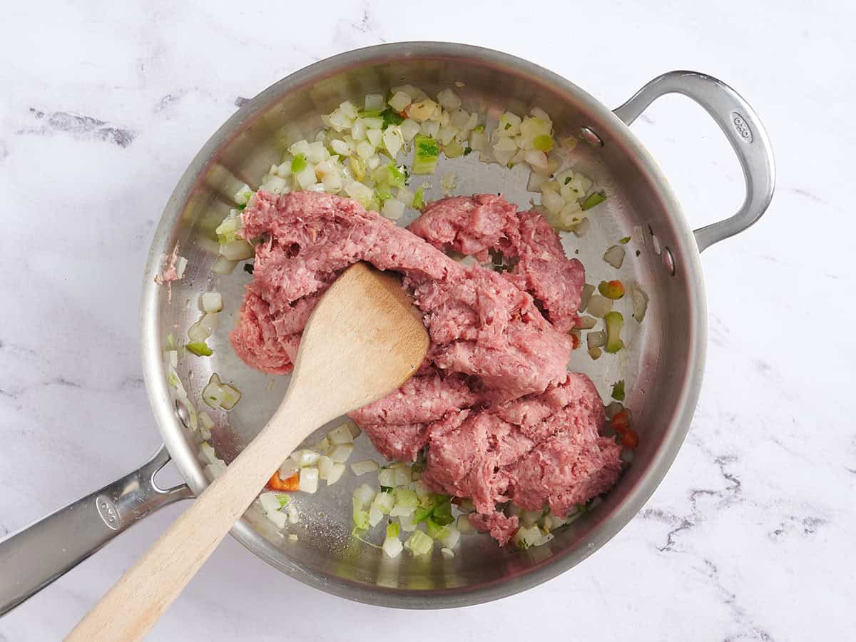 Carne molida y salchichas agregadas a pimientos y cebollas salteados.