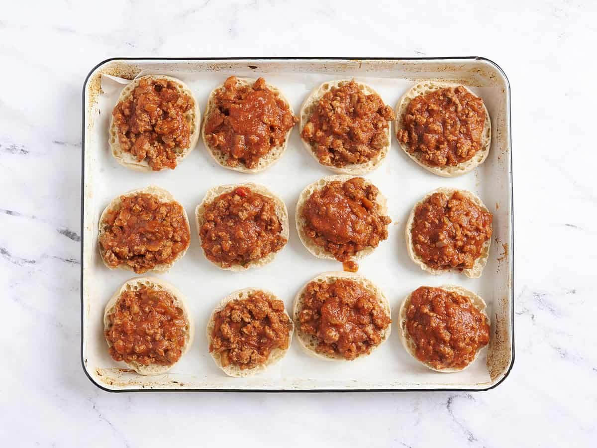 Salsa de carne agregada a rebanadas de muffin inglés cortadas por la mitad.
