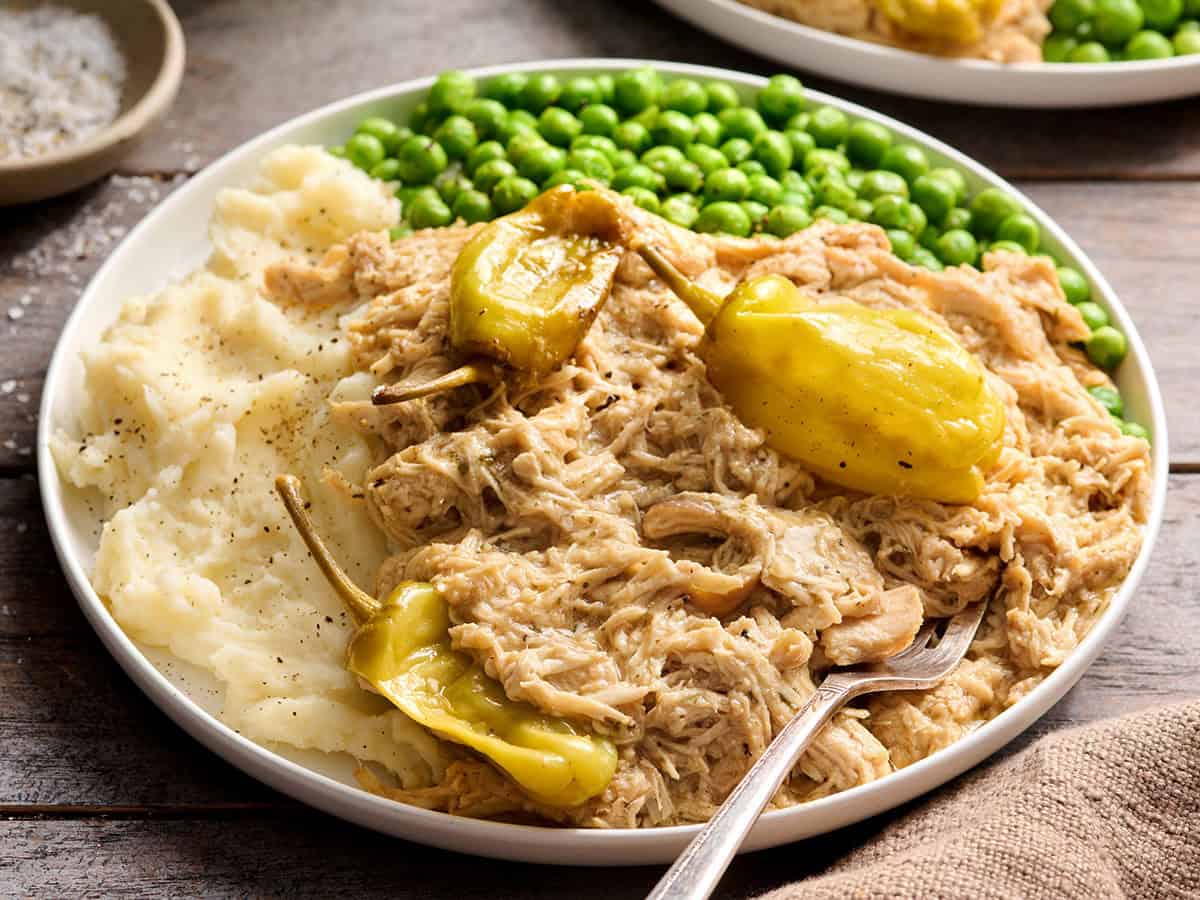 Pollo Mississippi en un plato con puré de patatas y guisantes.