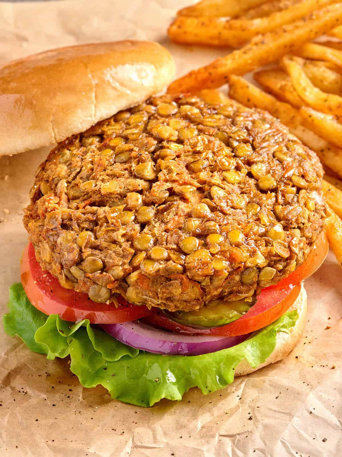 Vista lateral aérea de una hamburguesa de lentejas en un pan de hamburguesa, sin ensalada y sin el pan superior.