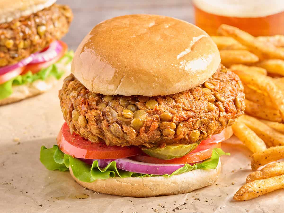 Vista lateral de una hamburguesa casera de lentejas en un pan de hamburguesa con ensalada.