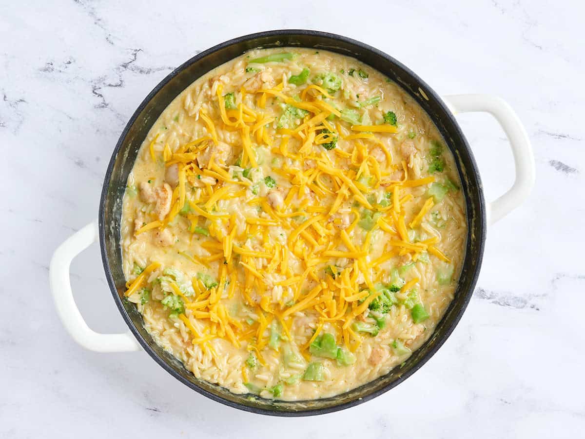 Queso cheddar espolvoreado sobre una sartén de cazuela de pollo y brócoli.
