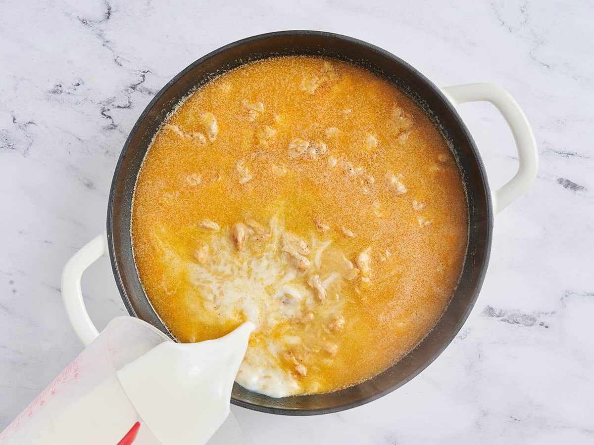 Se vierte la leche en una sartén con orzo, pollo y caldo.