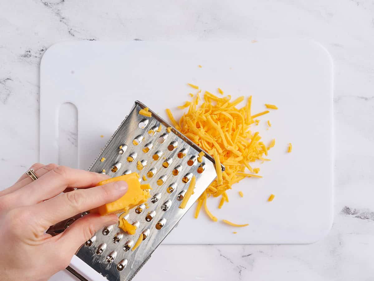 Una mano usando un rallador para rallar queso.
