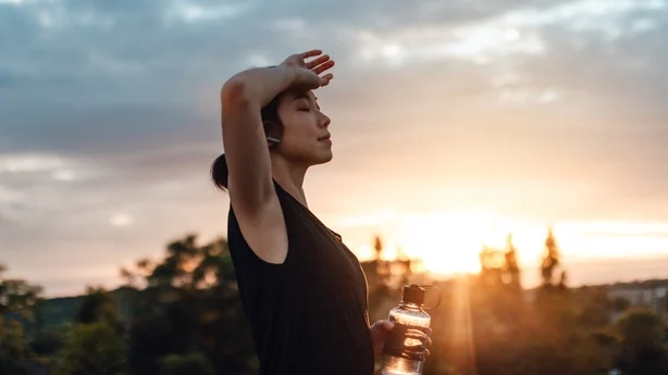 Mujer joven bebiendo agua, agotada después del entrenamiento diario