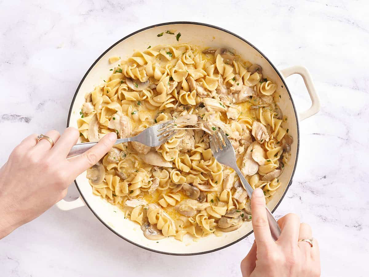Muslos de pollo desmenuzados en pollo stroganoff en una sartén.