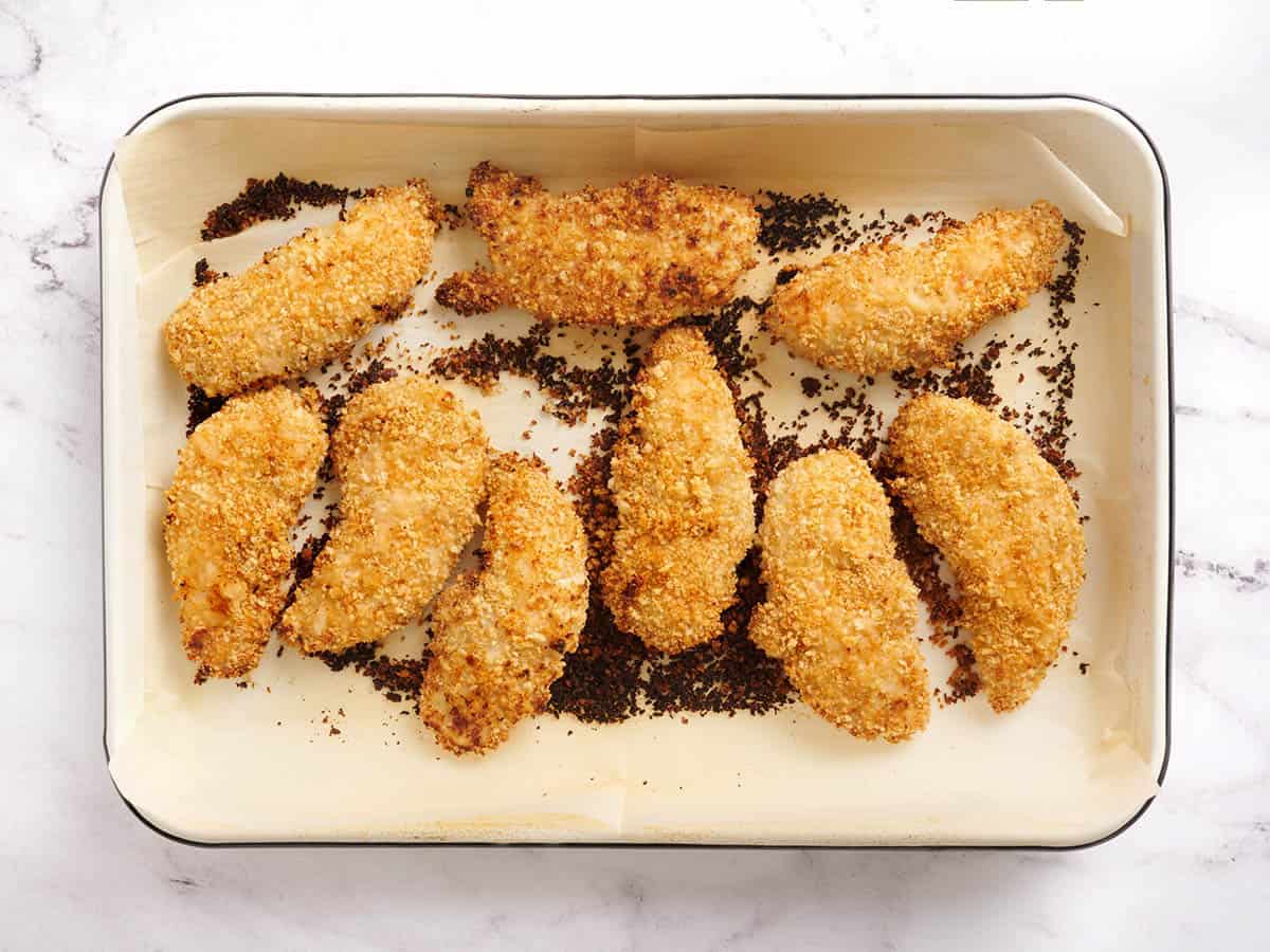 Trozos de pollo después de cocinarlos en una bandeja para hornear.