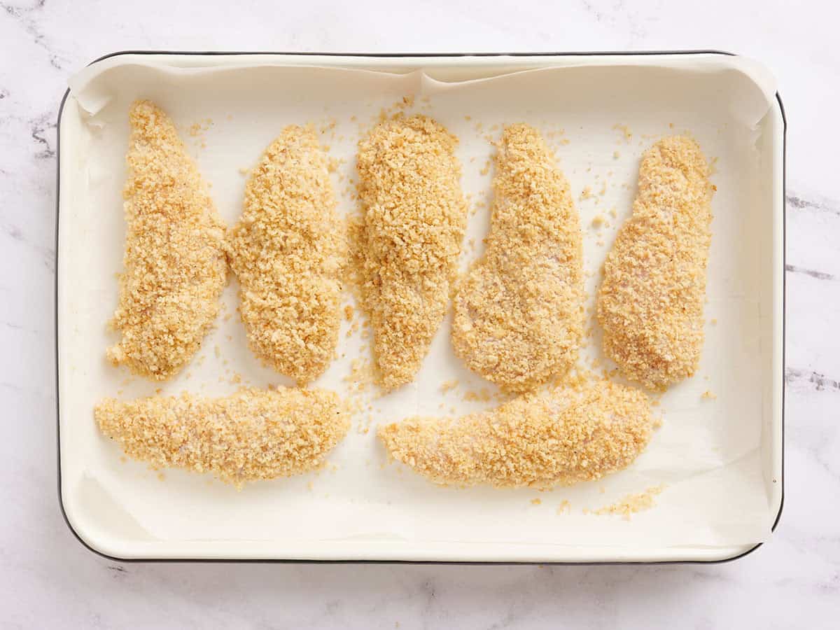 Trozos de pollo en una bandeja para hornear antes de hornear.