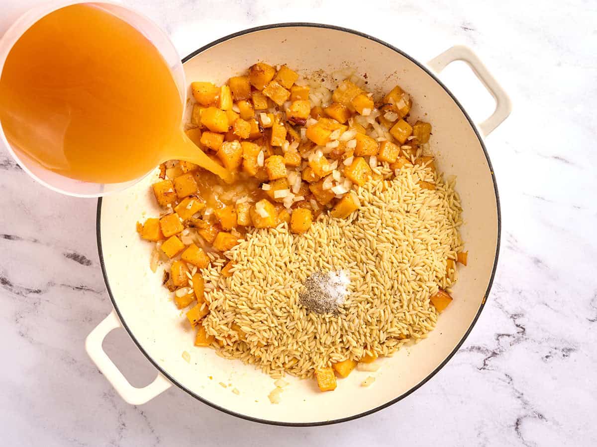 Calabaza en una sartén con orzo y condimentos, y vierta el caldo.